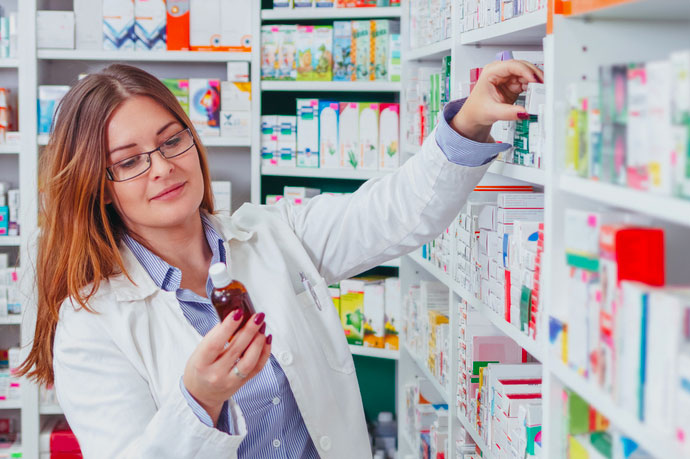 A pharmacist takes an item off a shelf